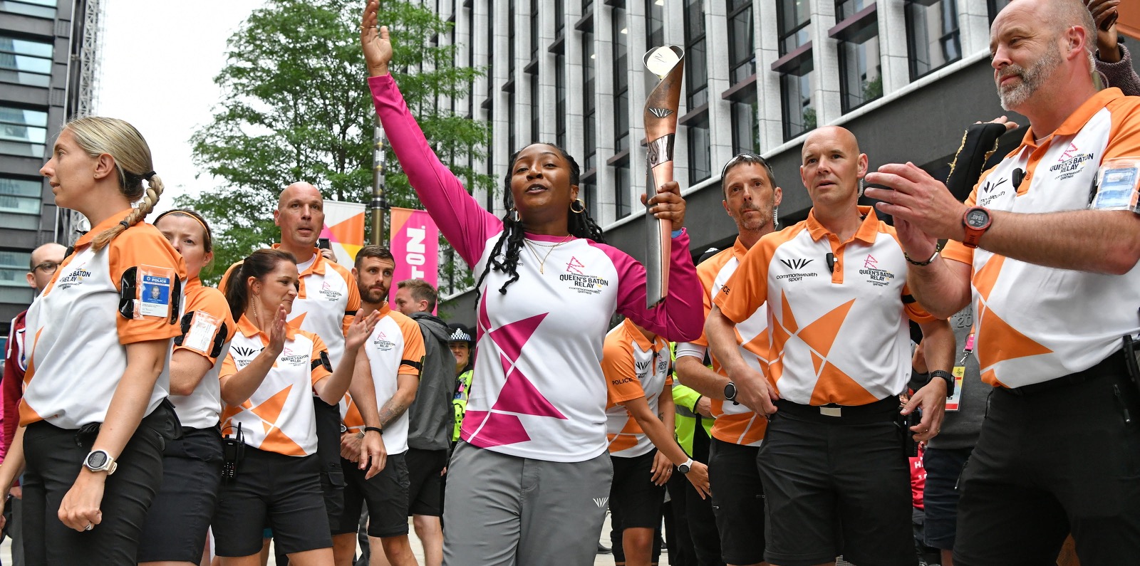 Sherelle Robbins carrying the Queens Baton through Paradise Birmingham before the start of the 2022 Commonwealth Games. She is surrounded by security runners and the public.